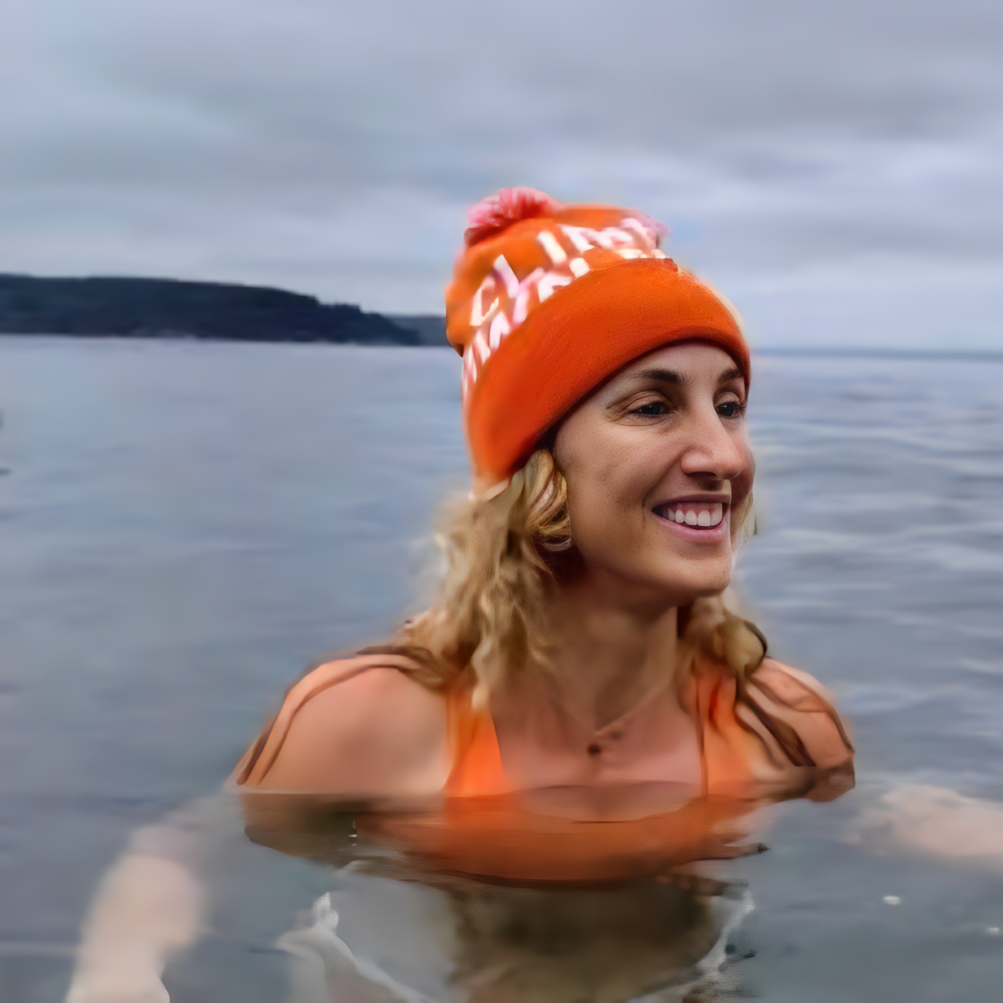 Woman practicing an open-water cold plunge with a warm hat, hormone-aware cold exposure for stress resilience.